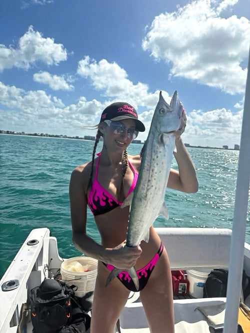Woman wearing Burnout Bombshell Flame Bikini with Bad Decisions hat on boat fishing lifestyle shoot